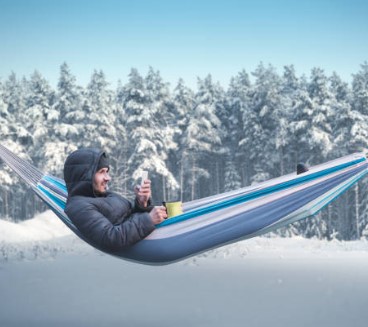 Zdjęcie przedstawia turystę w hamaku na tle zimowej scenerii Źródło: iStock